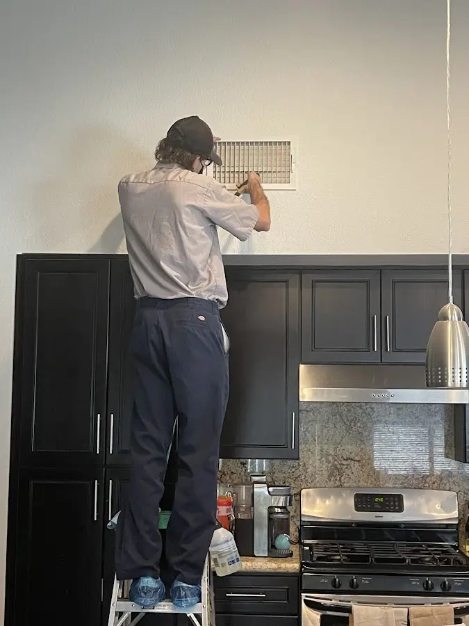 Technician inspecting an air vent during HVAC service in Brea